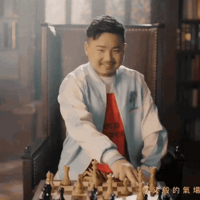 a man in a blue jacket is playing a game of chess with chinese writing behind him