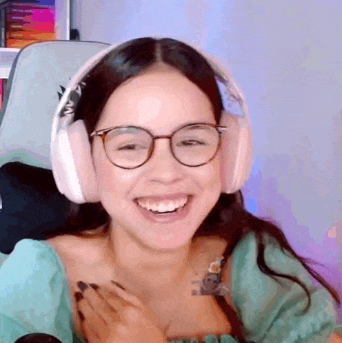a woman wearing headphones and glasses is smiling and laughing .