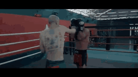 a man with a tattoo on his back is boxing in a gym