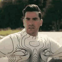a man wearing a white sweater with a pattern on it is sitting in a car .