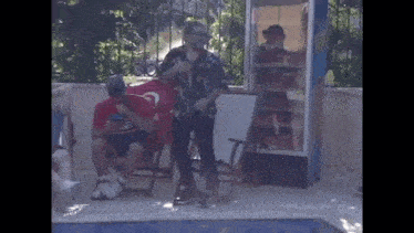 a group of people are standing around a pool .