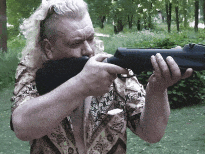 a man with long hair is holding a rifle in his hands