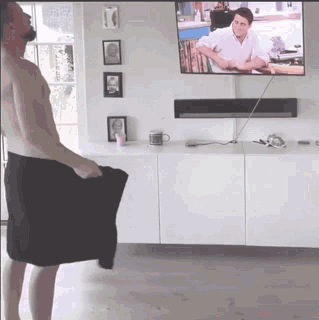 a shirtless man is standing in front of a flat screen television
