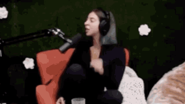 a woman wearing headphones is sitting in front of a microphone in a red chair .
