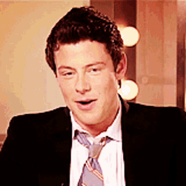 a man wearing a suit and tie is smiling