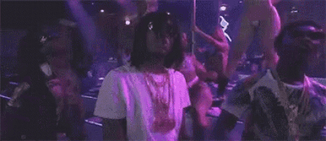 a group of people are dancing in a club in front of a purple light .
