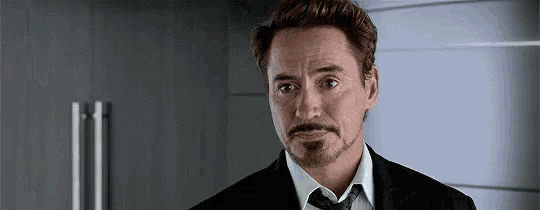 a man with a beard is wearing a suit and tie and looking at the camera .