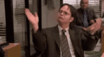 a man in a suit and tie is sitting in a room with his arms outstretched .