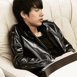 a man in a black leather jacket is sitting on a couch .