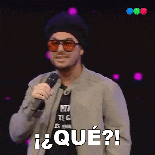 a man wearing sunglasses and a hat is holding a microphone and says qué