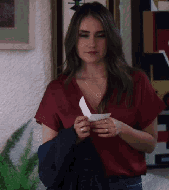 a woman in a red top holds a piece of paper