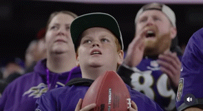 a young boy is holding a football in a stadium while watching a football game .