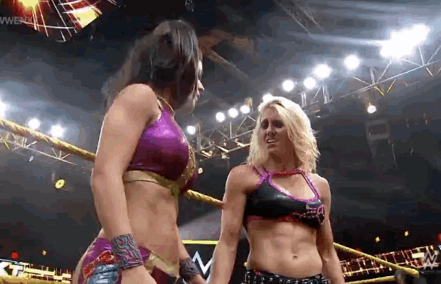two female wrestlers are holding hands in a wrestling ring .