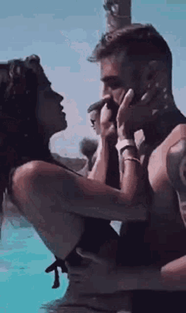 a man and a woman are kissing in a swimming pool . the woman is wearing a bikini .