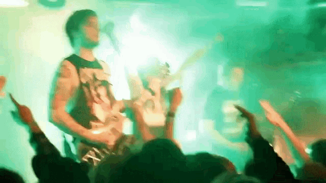 a man is playing a guitar in front of a crowd of people