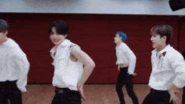 a group of young men are dancing in a room with a red wall .