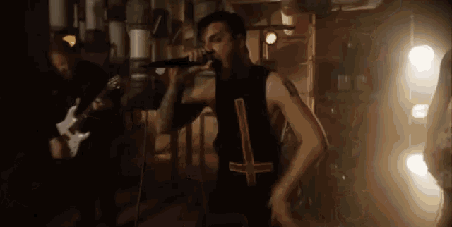 a man singing into a microphone while another man plays guitar