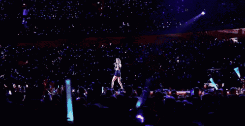 taylor swift is singing into a microphone on a stage .