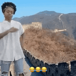a woman is dancing in front of the great wall of china .