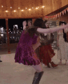 a woman in a purple dress is dancing in a room with other people
