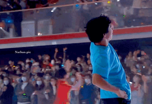 a man in a blue shirt is standing in front of a crowd with nathan.pic written on the bottom