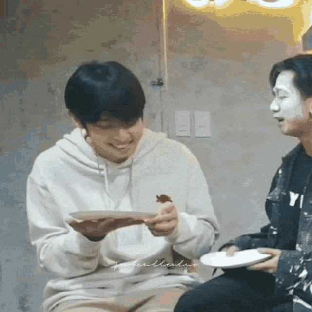 a man in a white hoodie holds a plate of food