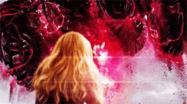 a woman with long blonde hair is standing in front of a giant red monster .