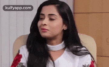 a woman is sitting in a chair with her eyes closed and looking at the camera .