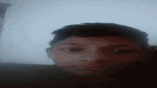 a close up of a young man 's face against a white wall