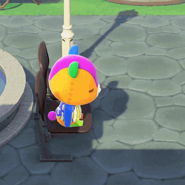 a stuffed animal with a purple and orange head sits on a bench