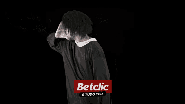 a man wearing sunglasses and a hat is blowing smoke behind a betclic logo