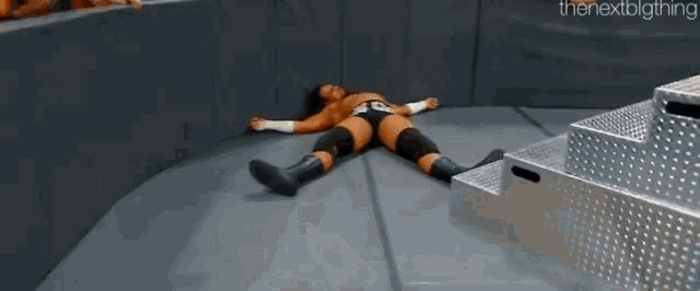 a wrestling wrestler is laying on the floor in a corner .