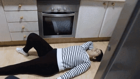 a woman in a striped shirt is laying on the floor in the kitchen