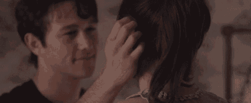 a man is touching a woman 's hair while they are looking at each other .