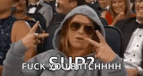 a woman wearing a hoodie and sunglasses is sitting in a crowd of people and says fuck you bitchhhh .