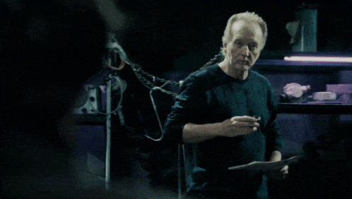 a man standing in a dark room holding a piece of paper and smoking a cigarette