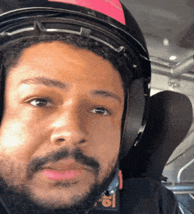 a close up of a man wearing a helmet with a pink stripe