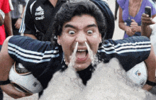 a man in a blue and white adidas shirt is holding a soccer ball