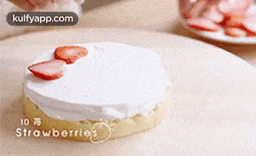 a cake with strawberries on top of it is being decorated with whipped cream .