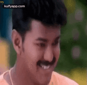 a man with a mustache is smiling and making a face .
