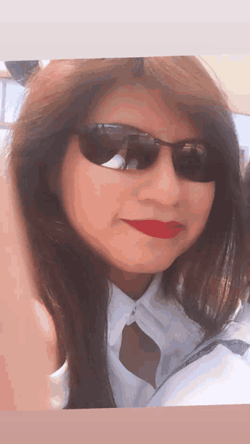 a woman wearing sunglasses and red lipstick smiles for the camera