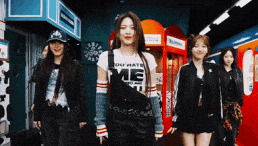 a group of girls are standing next to each other in front of a red phone booth .