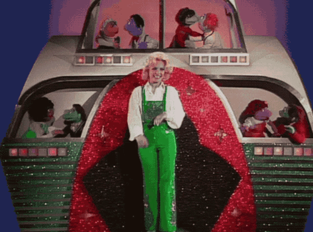 a woman in green overalls is standing in front of a giant red and green object