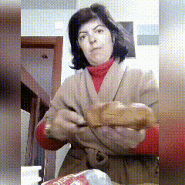 a woman in a red turtleneck is holding a bread loaf