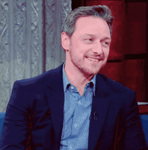a man in a suit and a blue shirt smiles