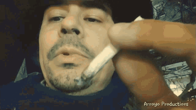 a man smoking a cigarette with the words arroyo productions written on the bottom
