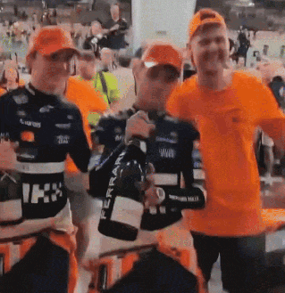 a group of men in orange shirts are holding bottles of ferrari wine