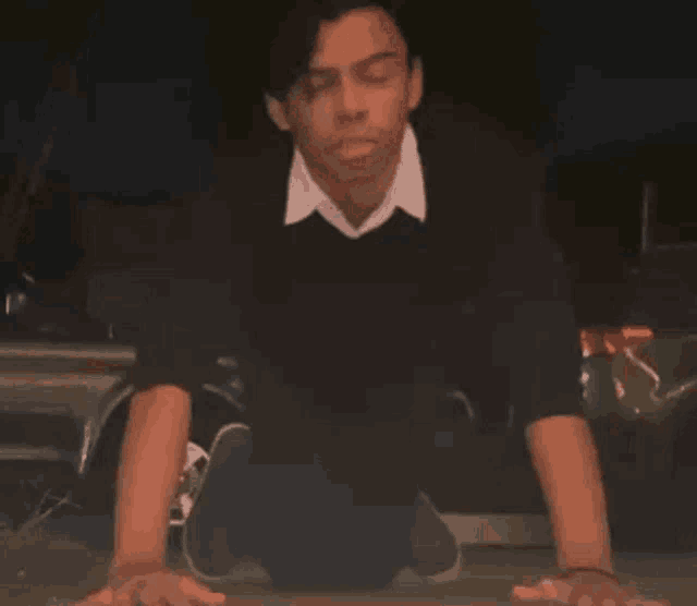 a man is kneeling down in front of a car with his hands on the ground