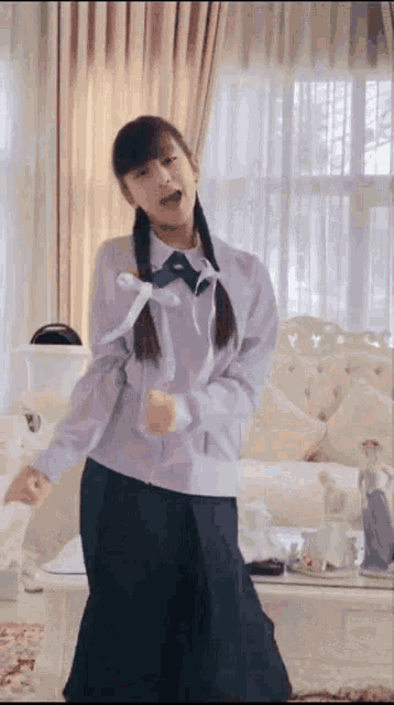 a girl in a school uniform is dancing in a living room .