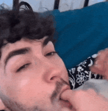 a man with a beard is laying on a bed with a blue pillow .